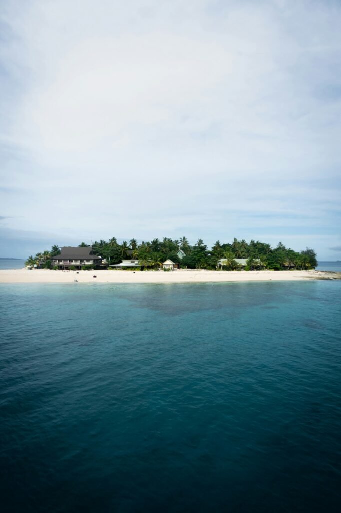 green trees on island surrounded by water under white clouds during daytime