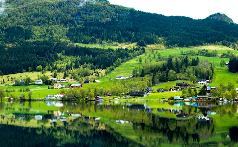 Beautiful landscape of Hol, Norway with hills, lake reflection, and rural houses.