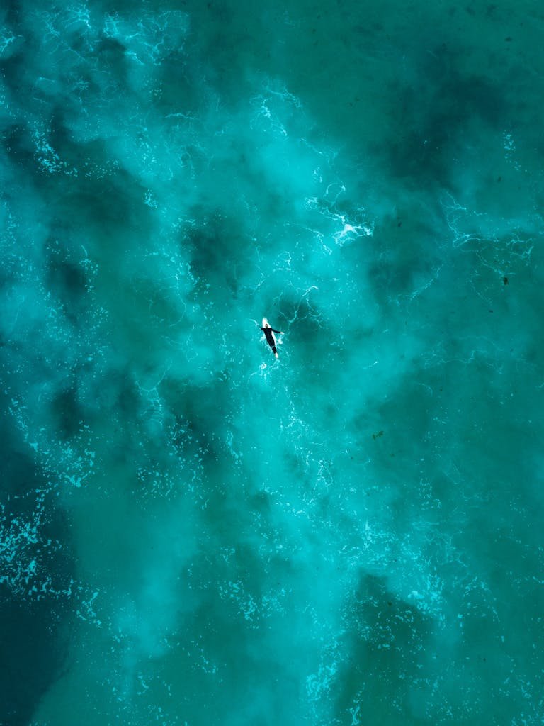 Breathtaking aerial shot of a lone surfer navigating the vibrant turquoise waters near Sydney.