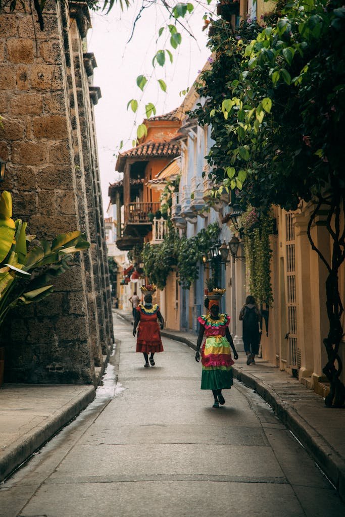 Colorful street scene in Cartagena, showcasing women in traditional attire amidst historic architecture.