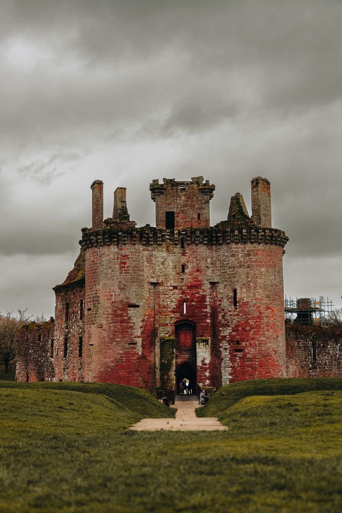 Majestic Caerlaverock Castle stands against a moody sky in Scotland, showcasing medieval architecture.