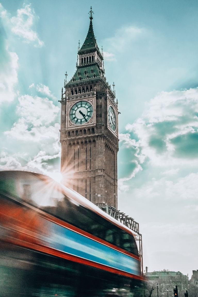 Dynamic shot of Big Ben with a red double-decker bus in motion, capturing urban London essence.